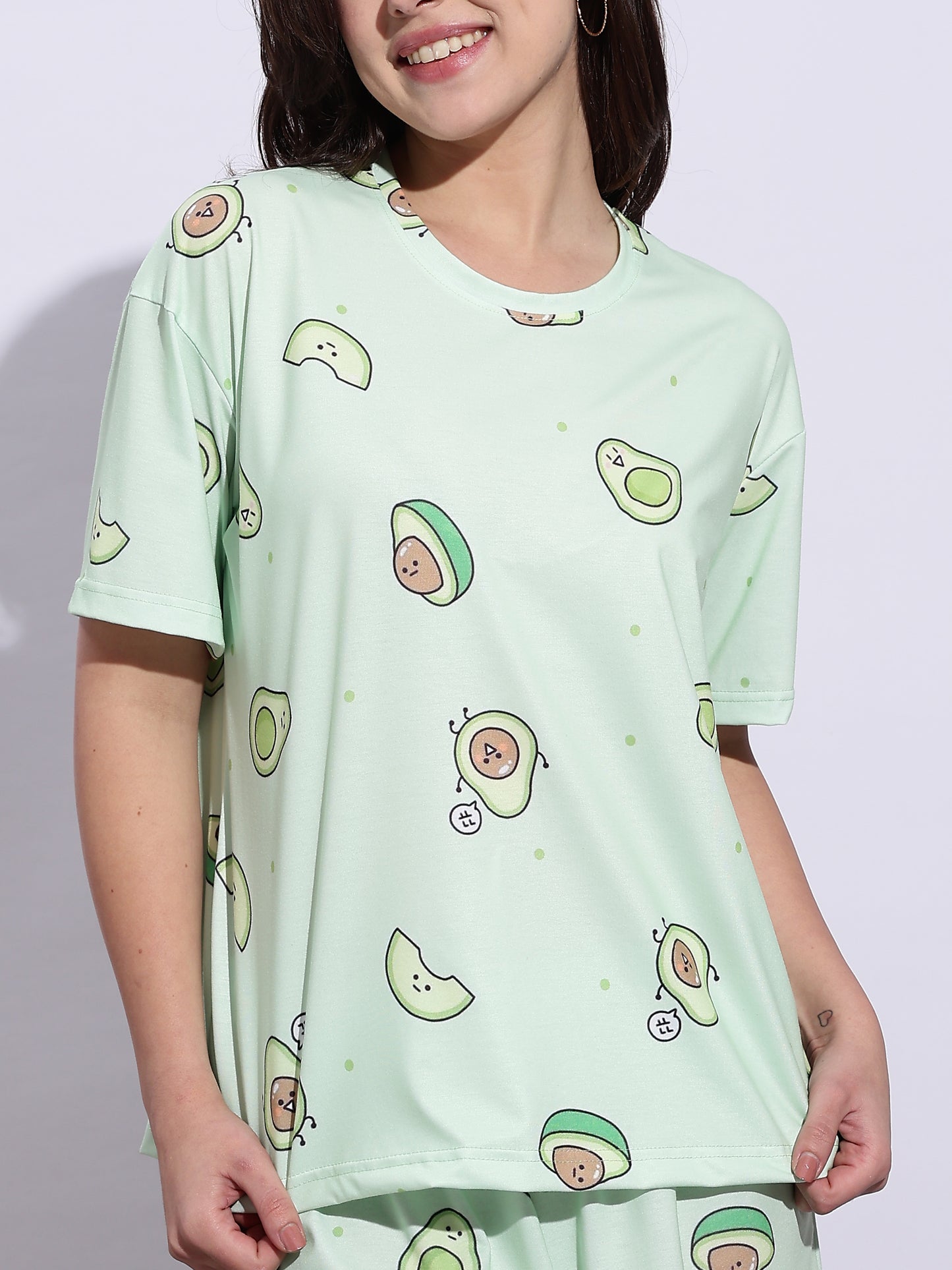 Person wearing a light green t-shirt with avocado pattern on a plain background