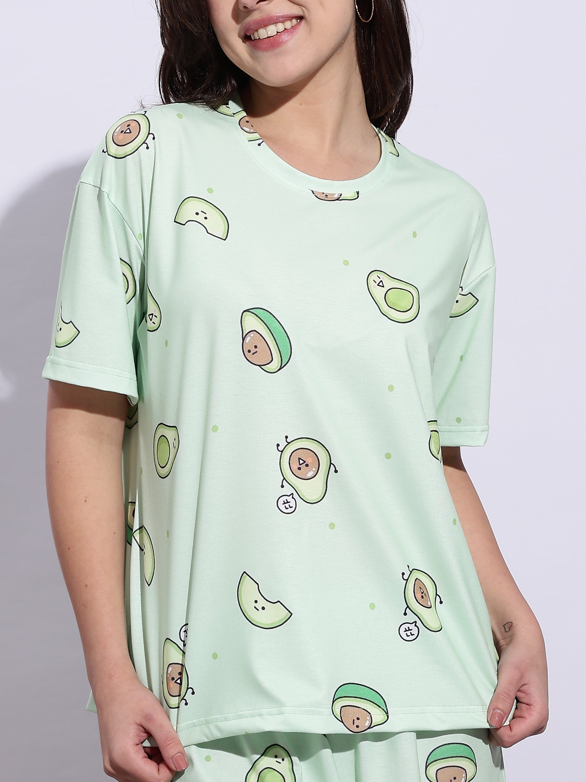 Person wearing a light green t-shirt with avocado pattern on a plain background