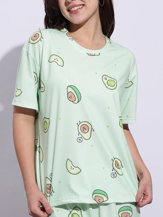 Person wearing a light green t-shirt with avocado pattern on a plain background